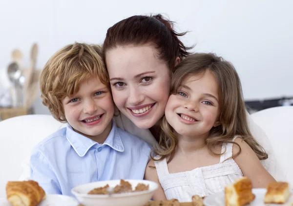 Smiling children having breakfast with their mother — Stock Photo, Image