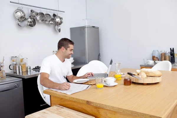 Hombre trabajando en la cocina mientras desayunaba — Foto de Stock