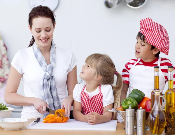 Mutter und Kinder schneiden Paprika in der Küche — Stockfoto