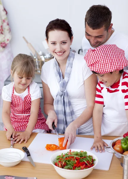 Glückliche Familie bereitet einen Salat in der Küche zu — Stockfoto