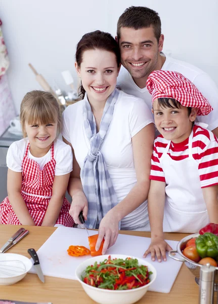 Família jovem cortando legumes na cozinha — Fotografia de Stock