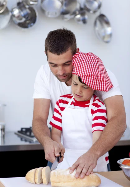 Pai ajudando seu filho a cortar pão — Fotografia de Stock