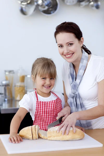 Smiling mother and daughter cutting bread — Stock Photo, Image