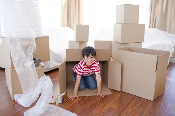 Ребенок играет с коробками в новом доме — стоковое фото