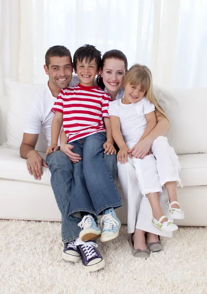 Smiling family sitting on sofa together — Stock Photo, Image
