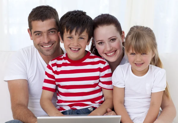 Lachende familie thuis met behulp van een laptop — Stockfoto