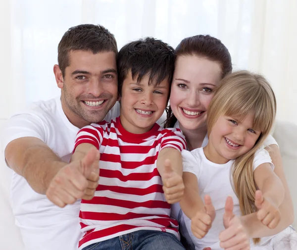 Family sitting on sofa with thumbs up — Stock Photo, Image