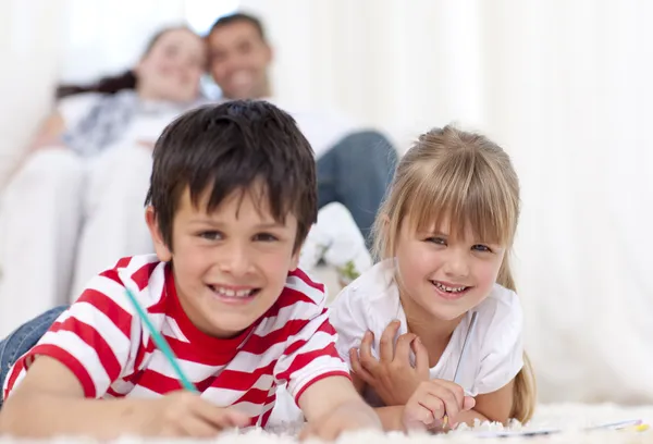 Smiling brother and sister painting on floor in living-room — Stock Photo, Image