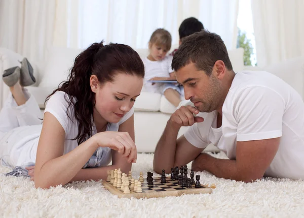 Parents jouant aux échecs sur le sol dans le salon — Photo