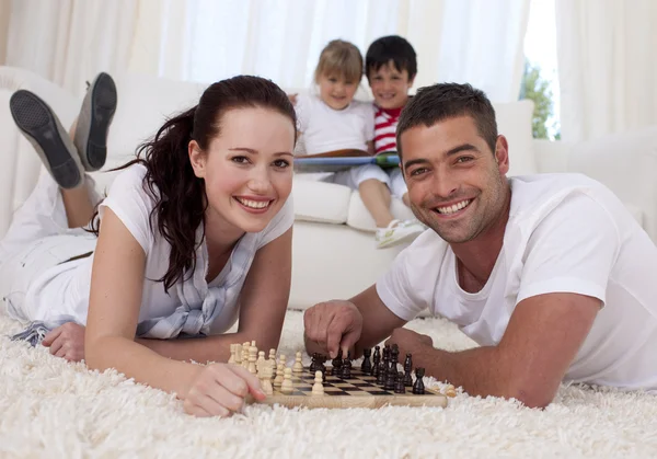 Šťastný pár hrát šachy na podlaze v obývacím pokoji — Stock fotografie