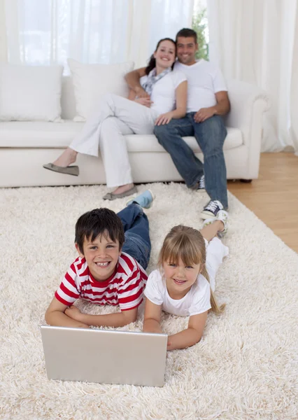 Crianças usando um laptop no chão na sala de estar — Fotografia de Stock
