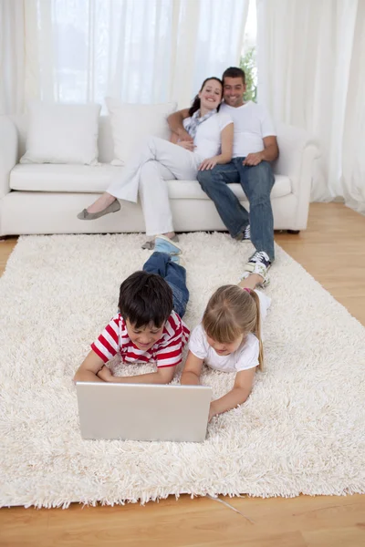Fratello e sorella utilizzando un computer portatile al piano in soggiorno — Foto Stock