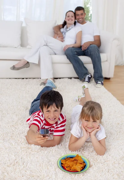 Bror och syster tittar på TV på golvet i vardagsrummet — Stockfoto