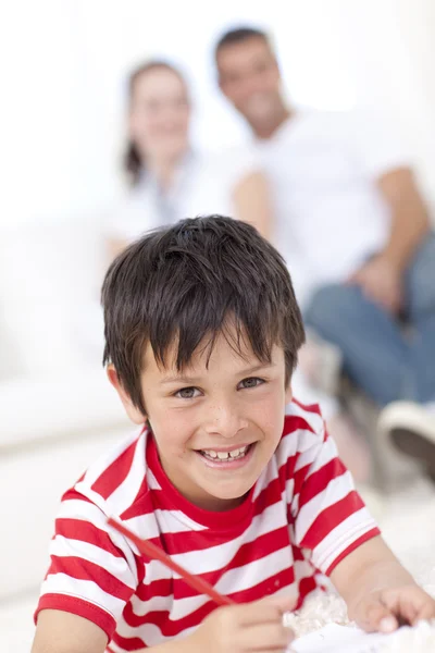 Niño sonriente pintando en el suelo en la sala de estar —  Fotos de Stock