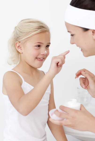 Mother and daughter putting cream on face — Stock Photo, Image