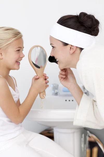 Little girl holding a mirror and mother putting makeup — Stock Photo, Image