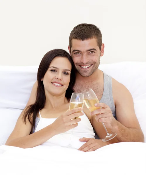 Pár tusting se šampaňským v posteli — Stock fotografie