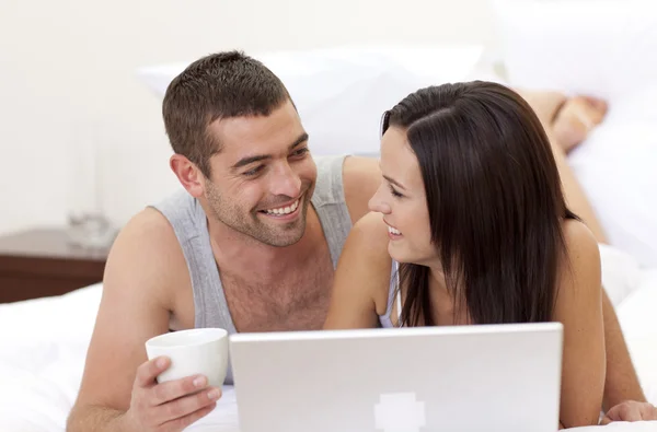 Karı koca yatakta bir dizüstü bilgisayar kullanarak — Stok fotoğraf