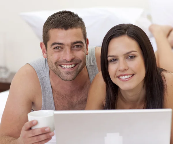 Retrato de casal na cama usando um laptop — Fotografia de Stock