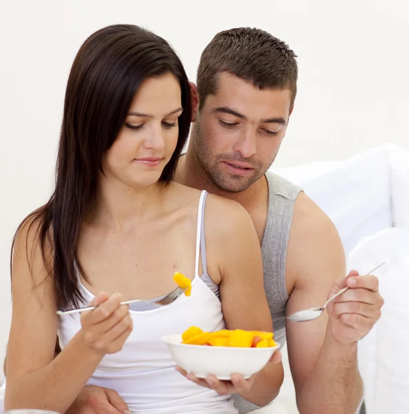 在床上吃水果的年轻夫妇 — 图库照片