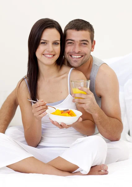 Couple eating fruit and orange juice in bed — Stock Photo, Image