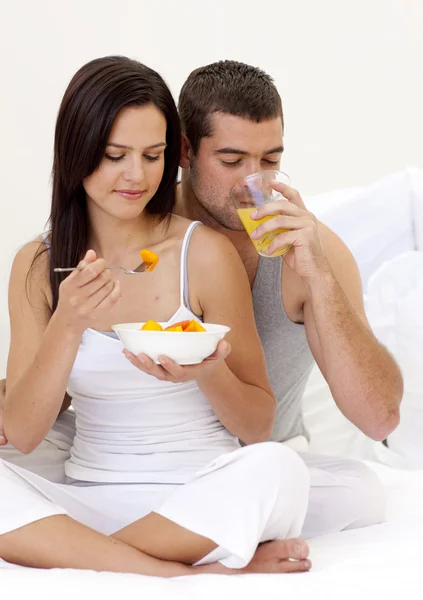 夫妇吃水果和喝橙汁，躺在床上 — 图库照片