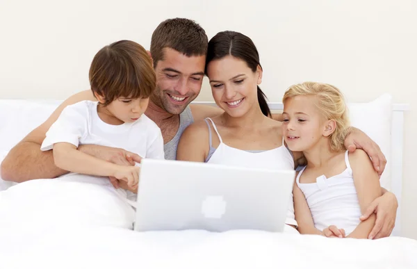 Famiglia utilizzando un computer portatile a letto — Foto Stock