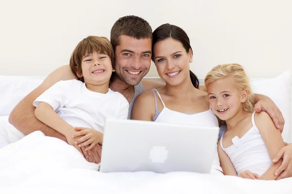 Portret van familie met behulp van een laptop in bed — Stockfoto