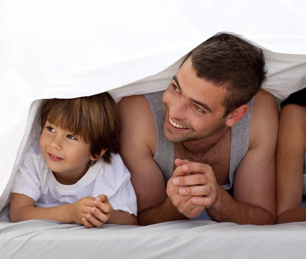 Sonrientes padre e hijo debajo de las sábanas — Foto de Stock