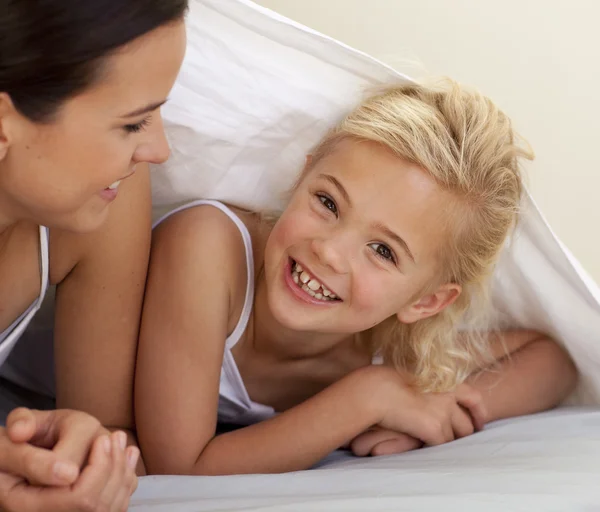Mother and daughter playing under the bedsheets — Stock Photo, Image