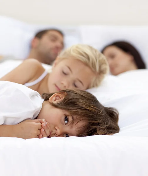 Mały chłopiec relaksując się przy jego rodzice i siostra śpi — Zdjęcie stockowe