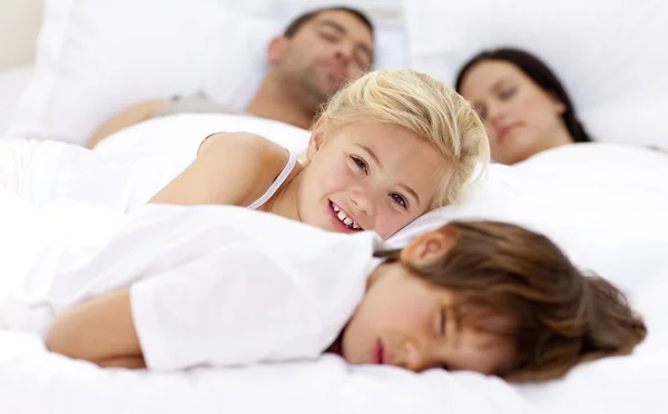 Lächelnde Tochter entspannt mit Bruder und Eltern im Bett — Stockfoto