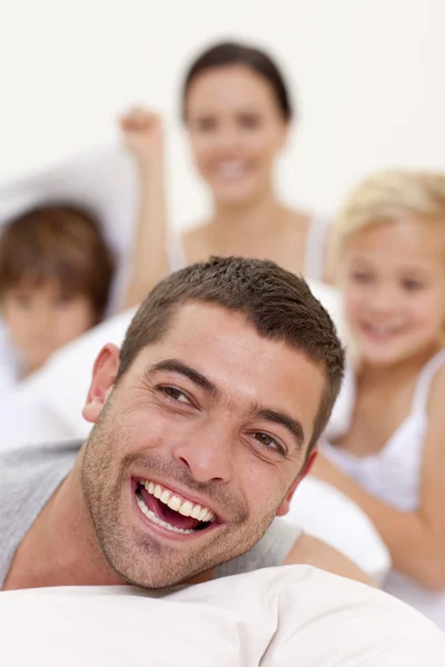 Portrait of father playing with family in bed — Stock Photo, Image