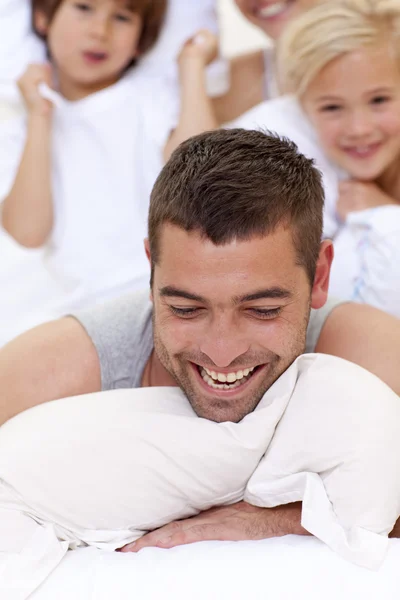 Family playing with father in bed — Stock Photo, Image