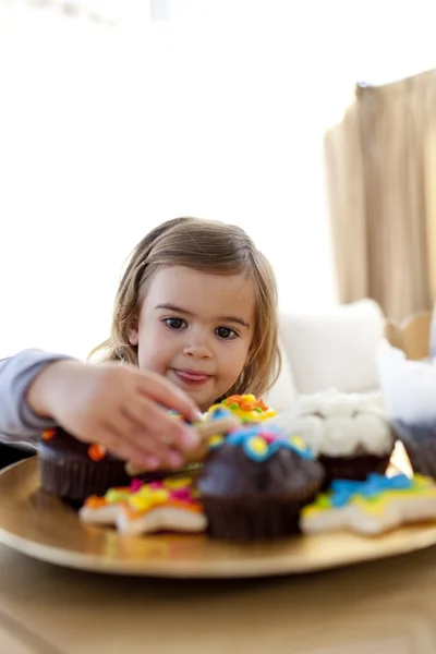 Hungry little girl looking at confectionery at home — Stock Photo, Image