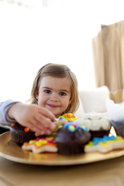Sorridente bambina mangiare dolciumi a casa — Foto Stock