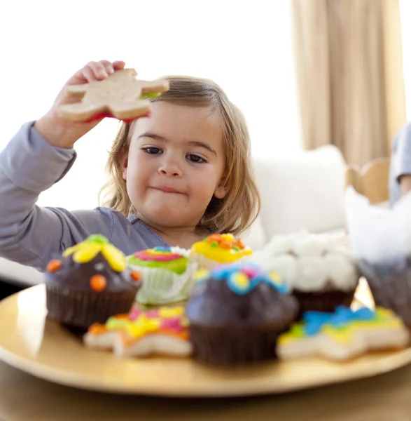 Menina feliz comendo doces em casa — Fotografia de Stock