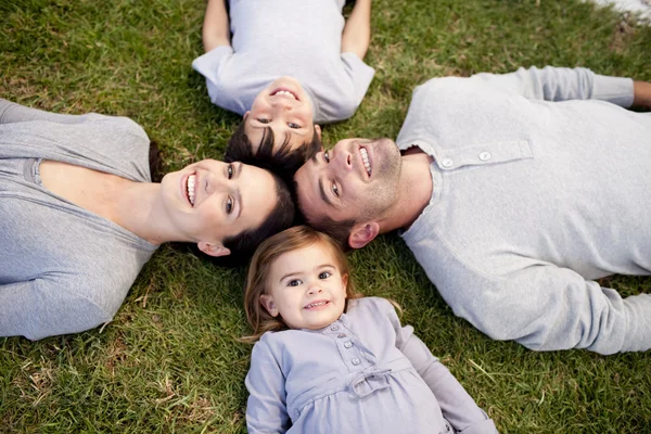 Familjen ligger i en park med huvuden tillsammans — Stockfoto
