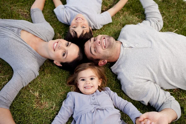 Küçük kızın ailesinin ve kardeşi ile bir parkta yalan — Stok fotoğraf
