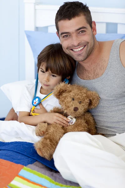 Father and sick son playing doctors in bed — Stock Photo, Image