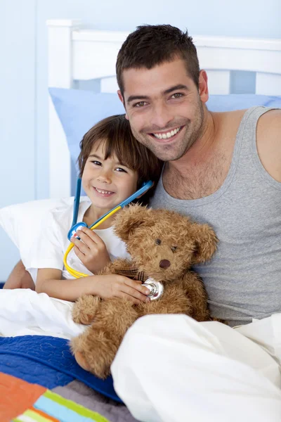 Отец и сын играют в доктора в постели — стоковое фото