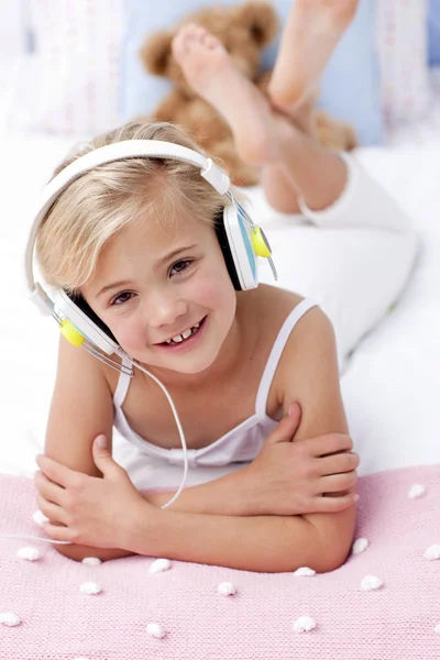 Portrait of little girl lying in bed listening to the music — Stock Photo, Image