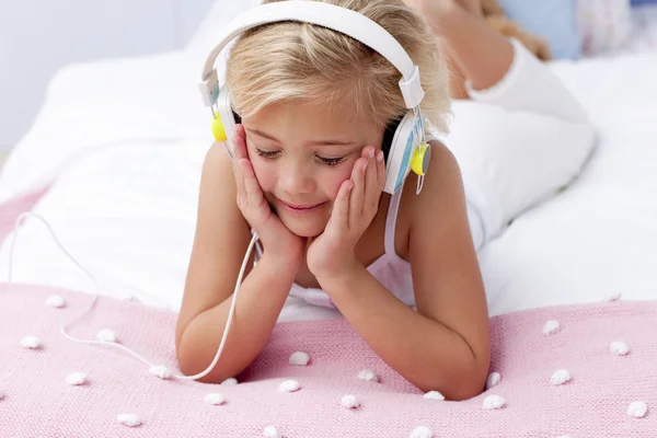 Klein meisje in bed luisteren naar de muziek — Stockfoto