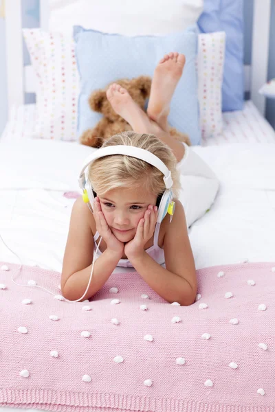 Κοριτσάκι ξαπλωμένη στο κρεβάτι, ακούει τη μουσική — Φωτογραφία Αρχείου