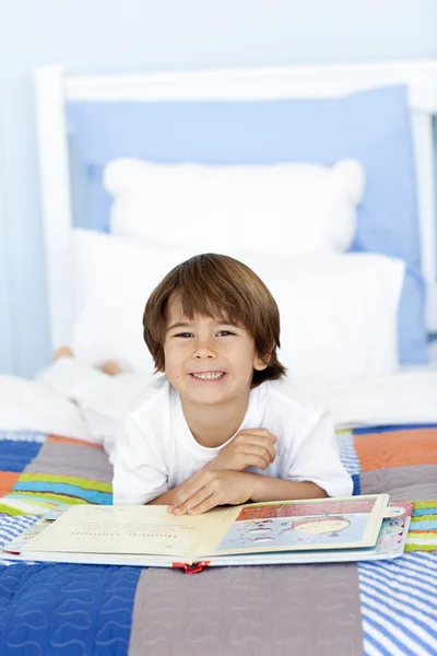 Küçük çocuk yatakta okuma gülümseyerek — Stok fotoğraf