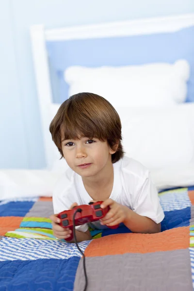 Junge in seinem Bett spielt Videospiele — Stockfoto