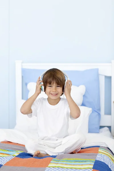 Küçük çocuk yatağının içinde müzik dinlemek — Stok fotoğraf