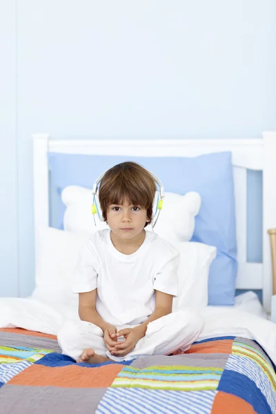 Triste niño escuchando música en la cama — Foto de Stock
