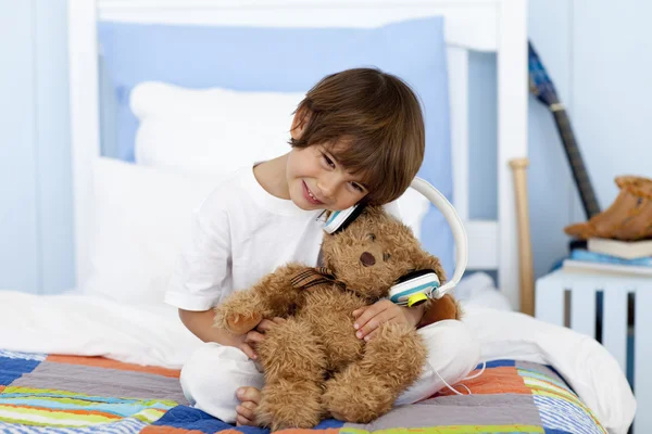 Kleine jongen speelt met hoofdtelefoons en teddy bear — Stockfoto