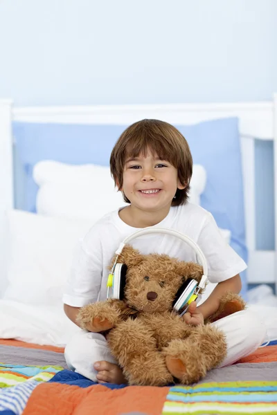 Glückliches Kind, das mit Kopfhörern und Teddybär spielt — Stockfoto